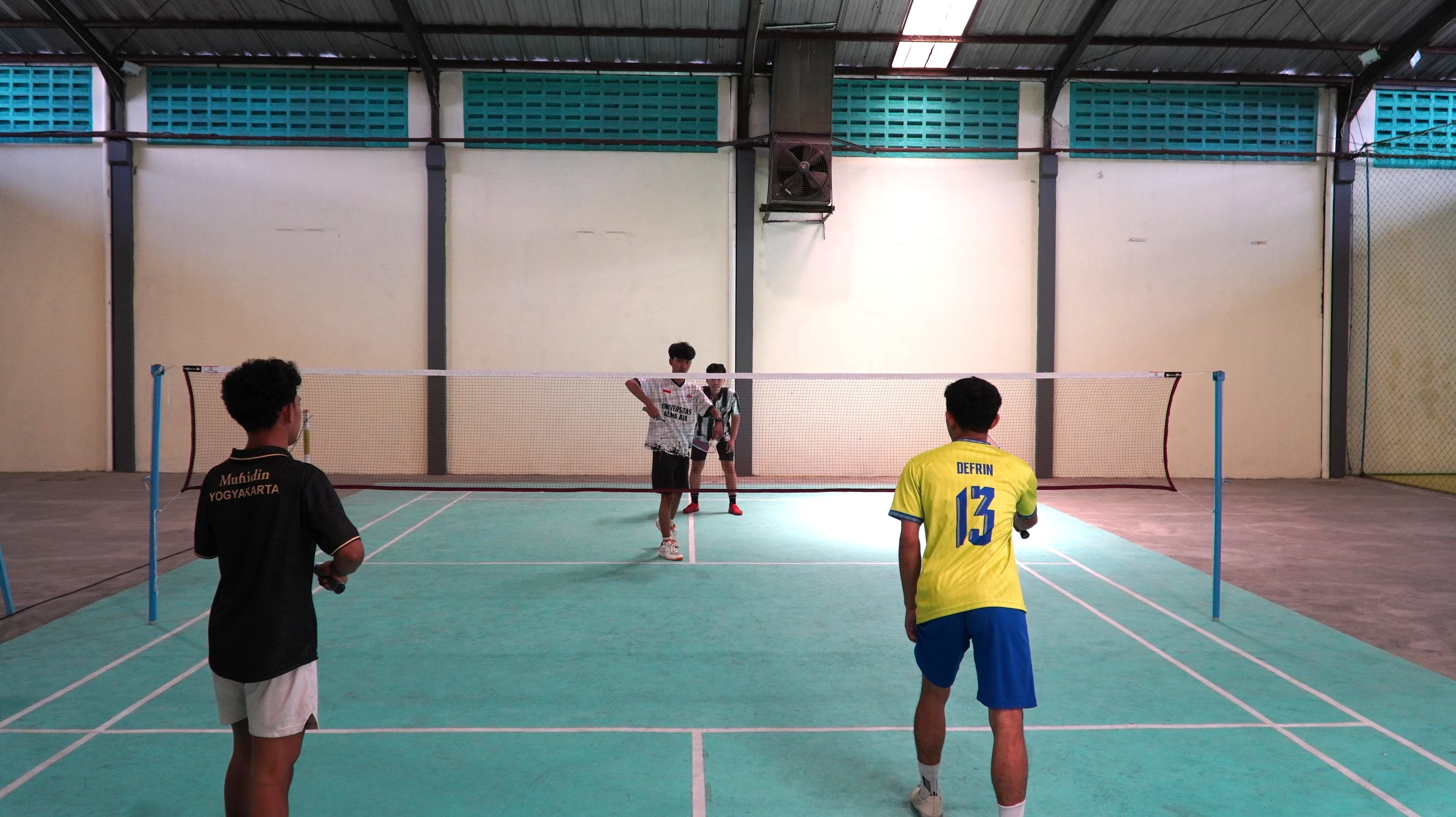Pemain bulu tangkis bertanding di lapangan indoor